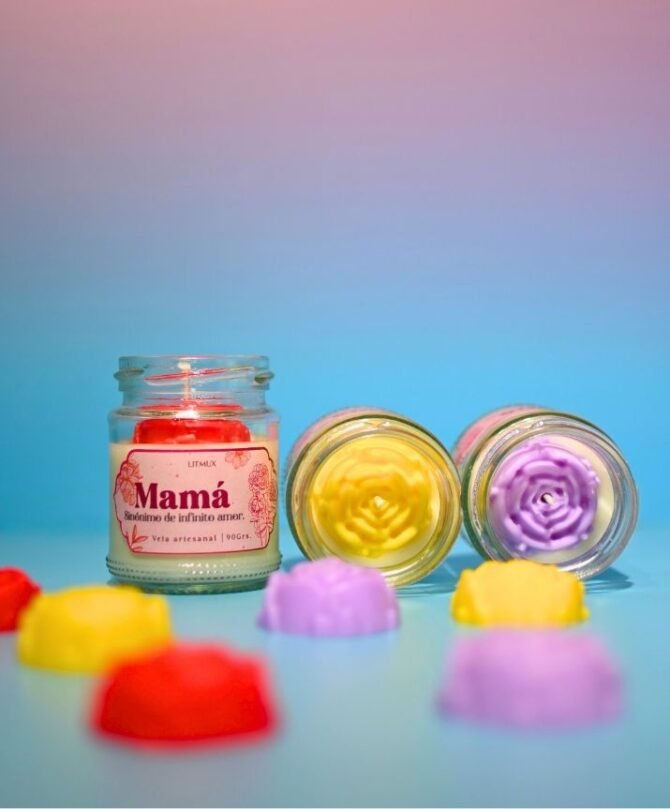 Vela artesanal con flor en cera, junto a rositas en cera decorativas.